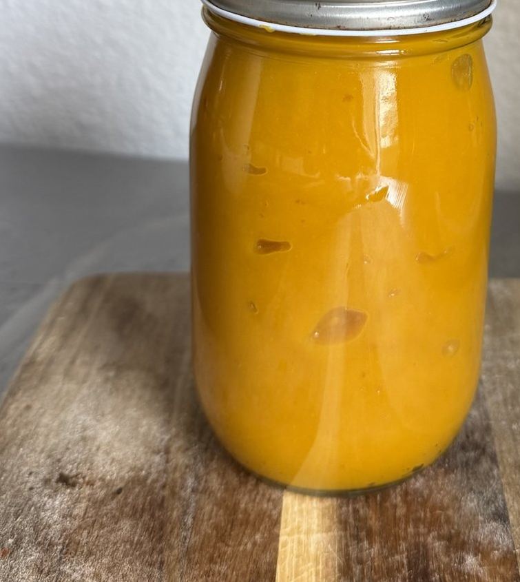Glass jar filled with bright orange homemade pumpkin puree