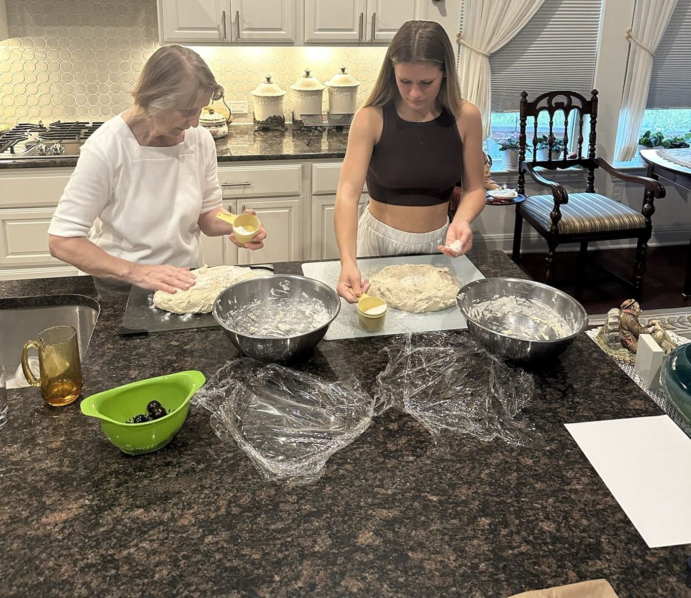 Emma and her grandmother Nana Donna kneading dough together at a kitchen island